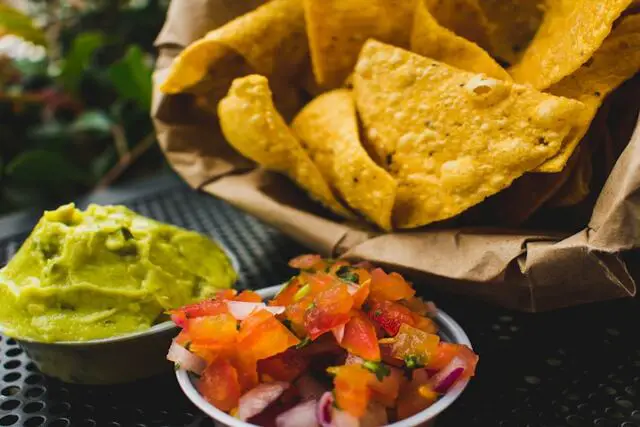 Nacho chip and smashed avocado with tomato salsa
